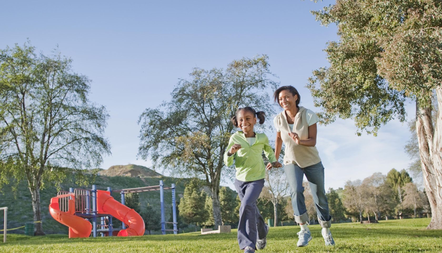 Mother and daughter running in a park