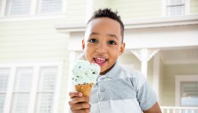 Mixed race boy eating ice cream cone in backyard