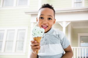 Mixed race boy eating ice cream cone in backyard