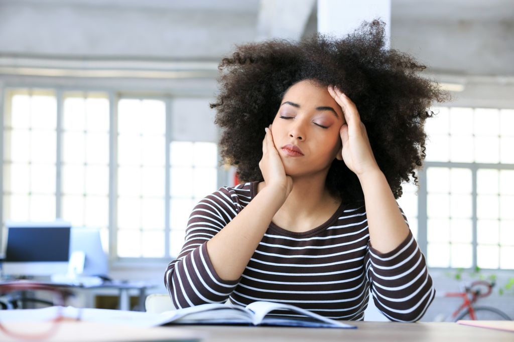 Young woman having headache at workplace