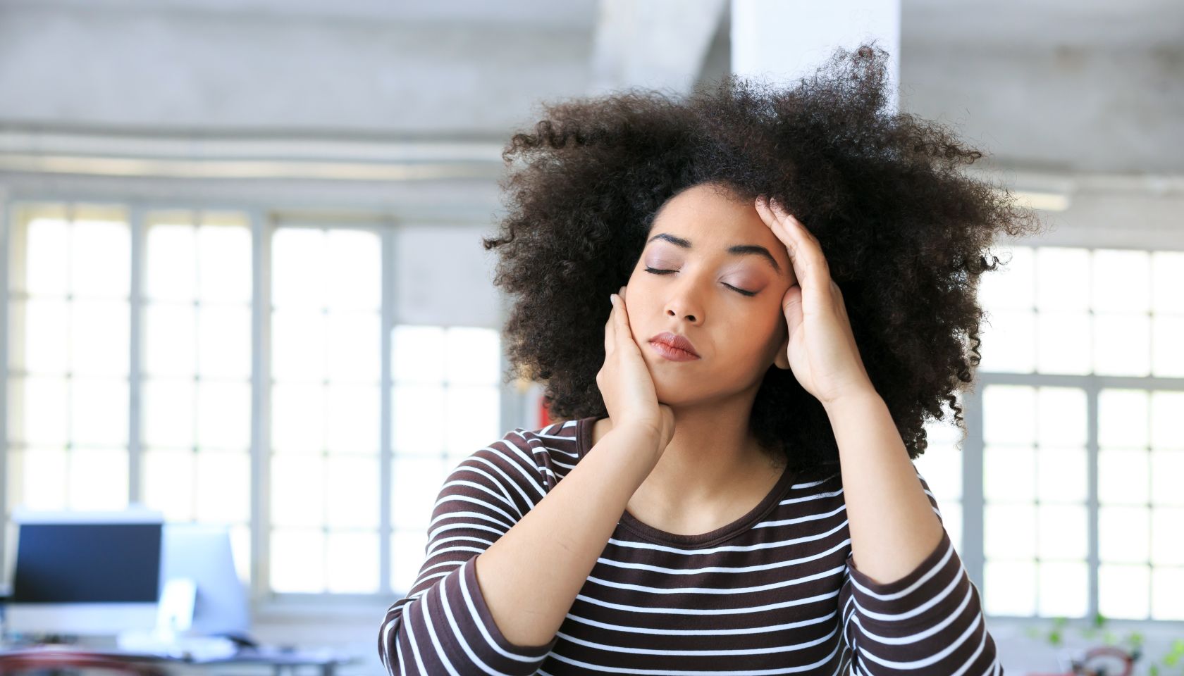 Young woman having headache at workplace