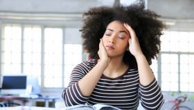 Young woman having headache at workplace