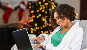 African American woman buying Christmas gifts online with credit card
