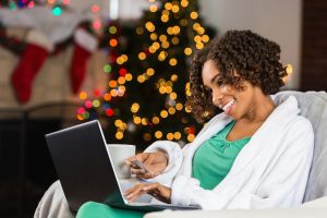 African American woman buying Christmas gifts online with credit card