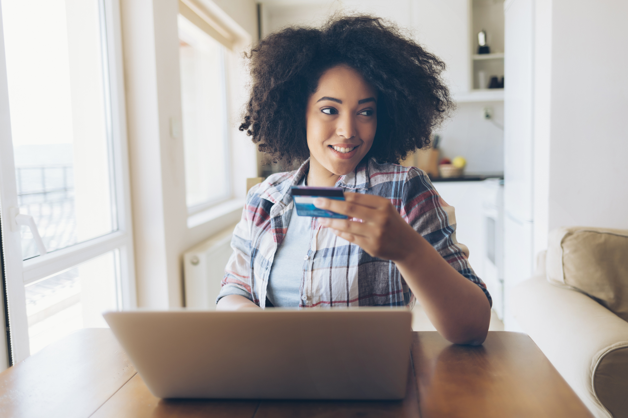 Woman using credit card and laptop at home