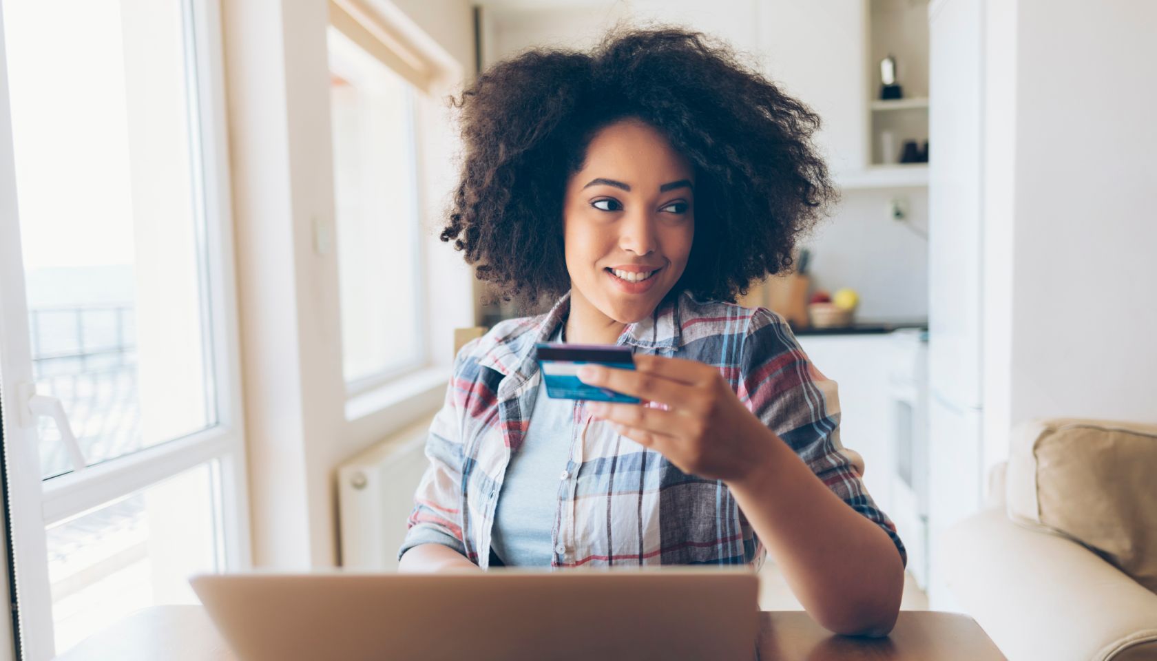 Woman using credit card and laptop at home