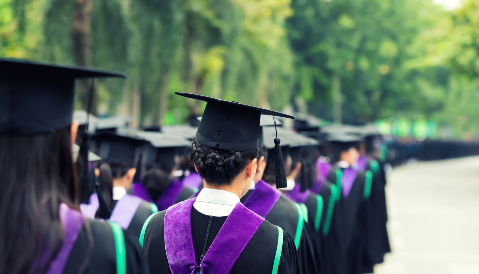 Back of graduates during commencement at university. Close up at graduate cap. Color tone image.
