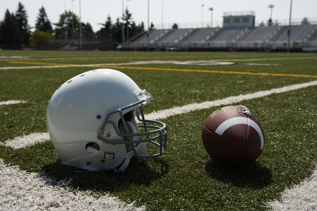 Football and football helmet on football field