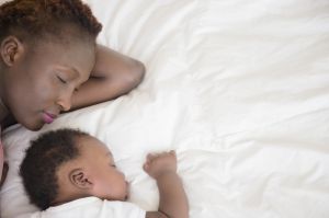 Black mother and son sleeping on bed